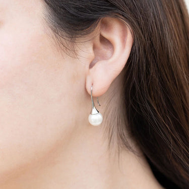 Pearl earring worn by a person with brown hair.