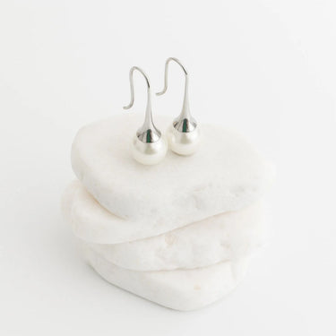 Silver earrings on a white marble surface
