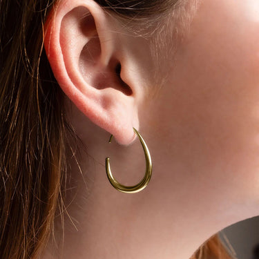 Gold hoop earring worn by a person with brown hair.