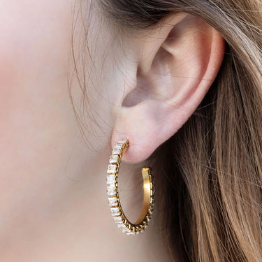 Gold hoop earrings worn by a person with a blurred background