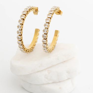 Gold hoop earrings with clear gemstones on a white background