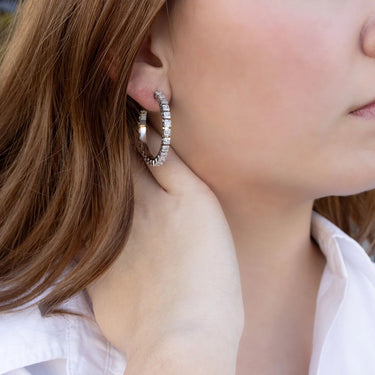 Close-up of a person wearing hoop earrings with a blurred background
