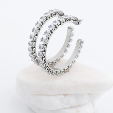 Silver hoop earrings with clear gemstones on a white background