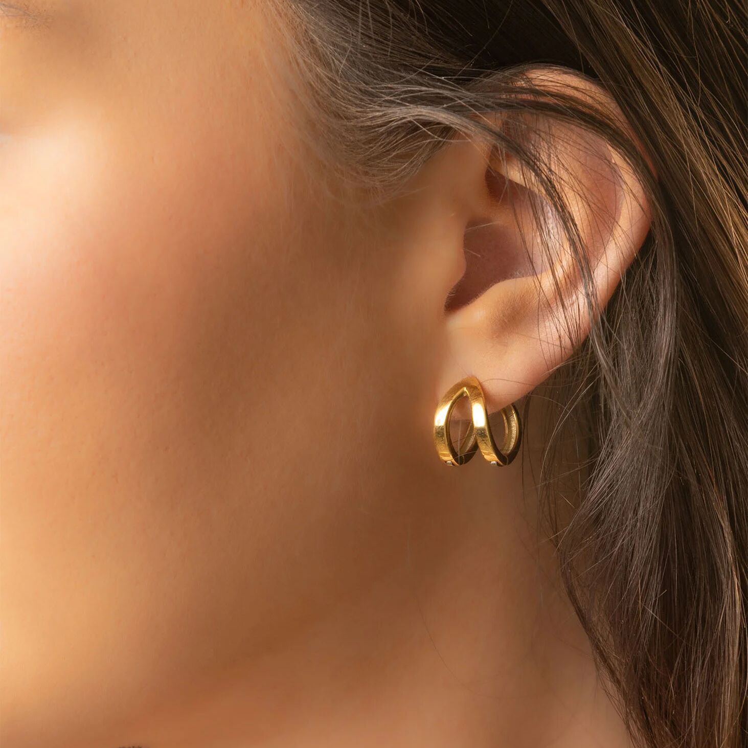 Gold hoop earrings worn by a person with brown hair.