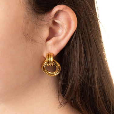 Gold hoop earring worn by a person with dark hair.