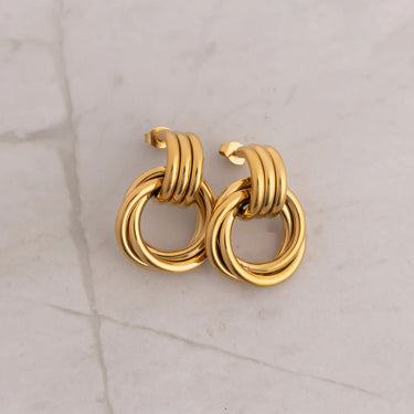 Pair of gold hoop earrings on a light gray marble surface