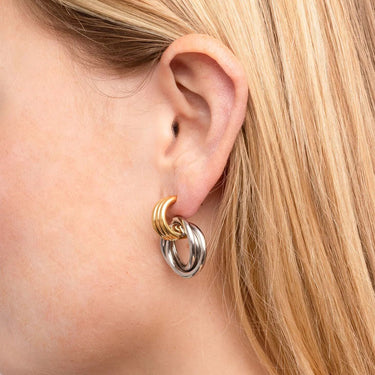 Close-up of an ear wearing a gold and silver hoop earring.