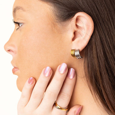 Close-up of a woman wearing a gold hoop earring with a plain background