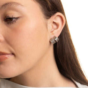 Close-up of a woman wearing a silver hoop earring with a neutral background