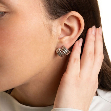 Close-up of a person wearing a silver earring with a hand adjusting it.