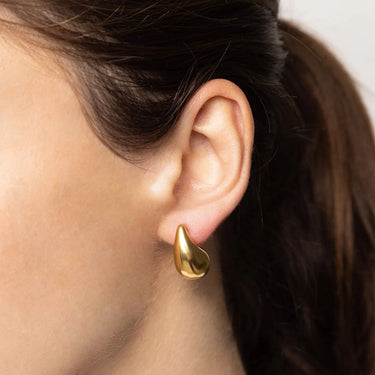 Gold earring worn by a person with a neutral background