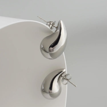 Silver teardrop earrings on a light gray background