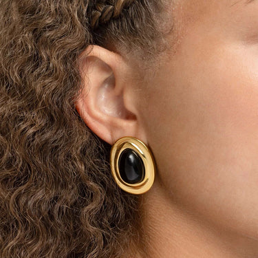 Gold Black Enamel Stud Earrings worn by a person with curly hair.