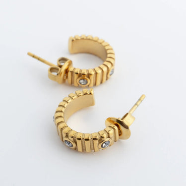 Gold hoop Fluted Huggie with Stones Earrings with embedded stones on a light gray background
