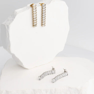 Gold and silver hoop earrings on a white stand with a white background