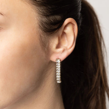 Close-up of an ear wearing a hoop earring with a neutral background