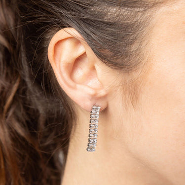 Close-up of an ear wearing a silver hoop earring with a blurred background