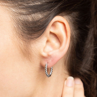 Close-up of an ear wearing a silver hoop earring with a blurred background