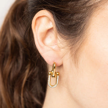Gold hoop earring with a small diamond on an ear