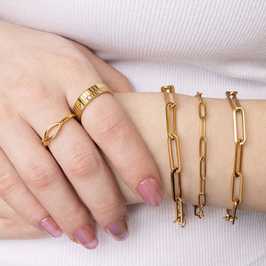 Gold jewelry including rings and bracelets on a hand against a white background
