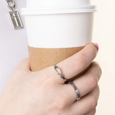 Hand holding a coffee cup with two rings on a plain background