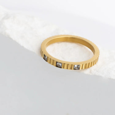 Gold ring with embedded stones on a light gray background