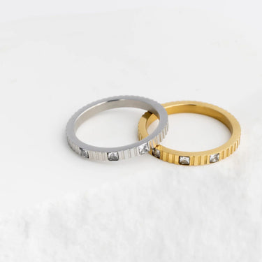 Two rings, one silver and one gold, on a white background