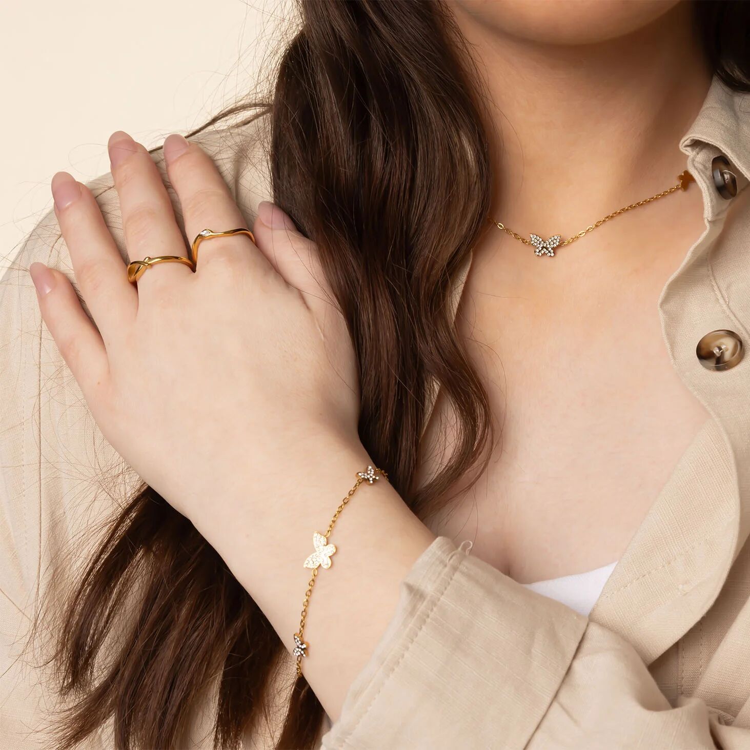 Close-up of a person wearing gold jewelry including a bracelet, ring, and necklace.