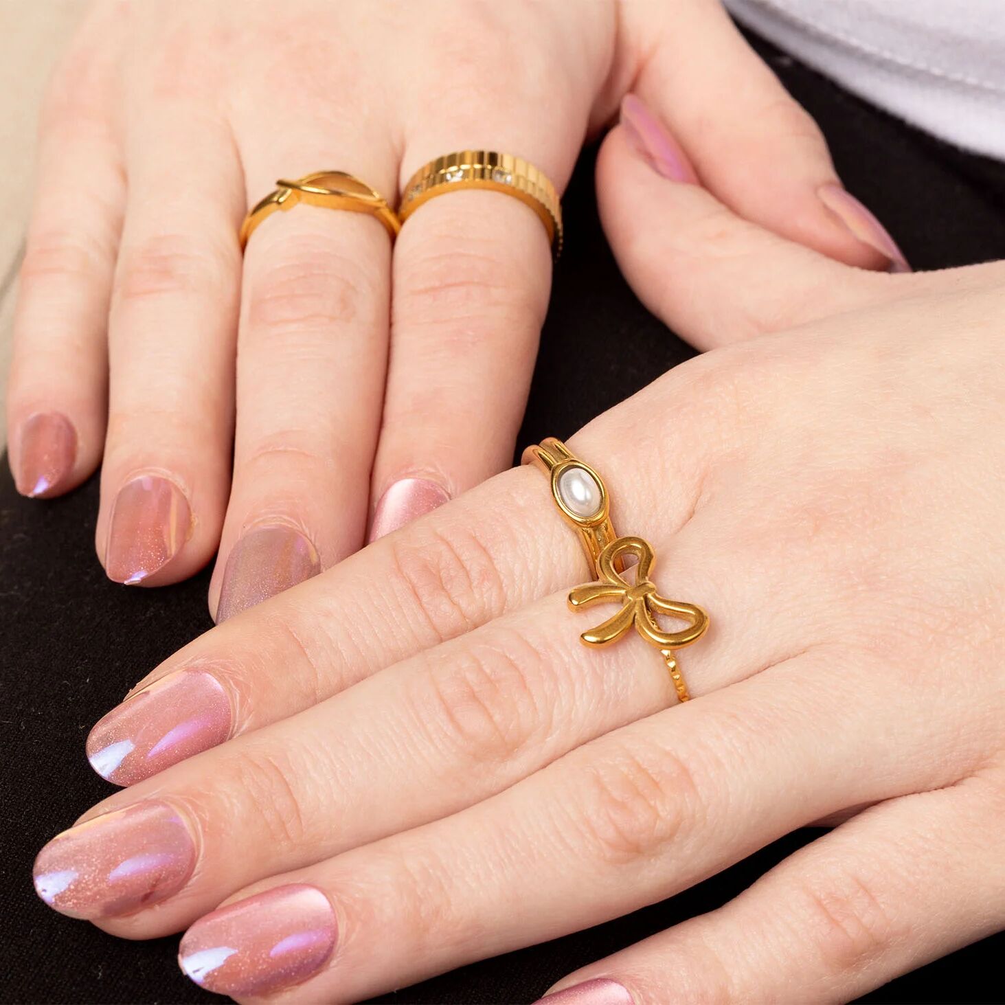 Close-up of hands wearing gold rings with a decorative bow design.