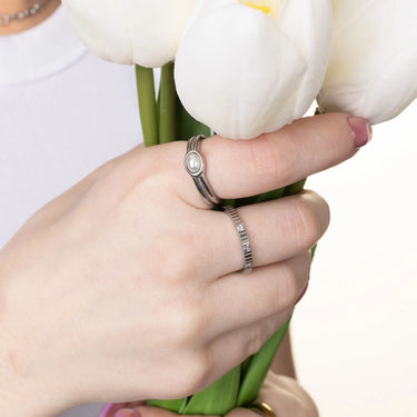 Hand holding a bouquet of white tulips with two rings on a blurred background