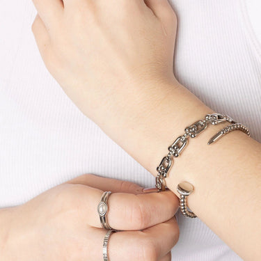 Close-up of a wrist wearing a silver bracelet and rings on a white background