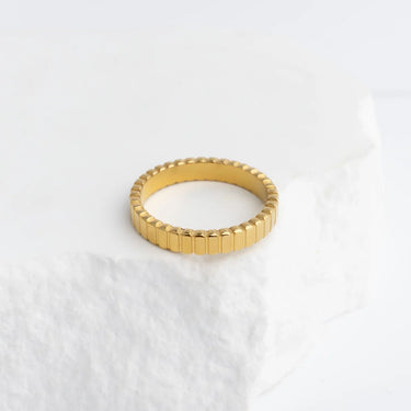 Gold ring with a textured band on a white background