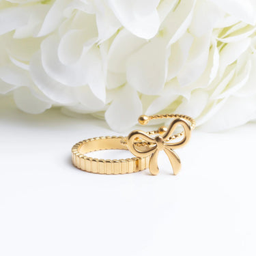 Gold bow-shaped ring on a white floral background
