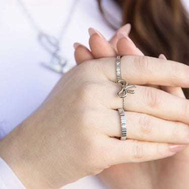Close-up of a hand wearing two silver rings with a blurred background