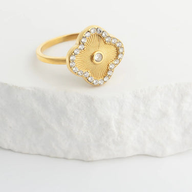 Gold Floral Motif Ring with a decorative design on a white stone surface