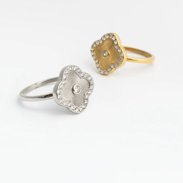 Two heart-shaped Floral Motif Rings, one silver and one gold, on a white background
