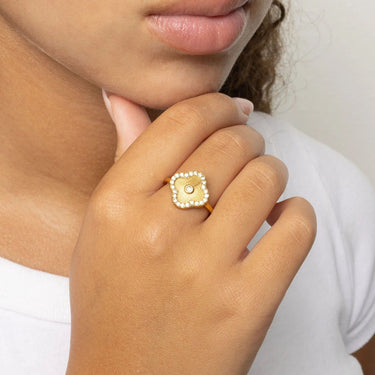 Gold Floral Motif Ring with a central gemstone on a person's finger