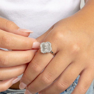 Close-up of a hand wearing a silver Floral Motif Ring with a CZ stones on a white background