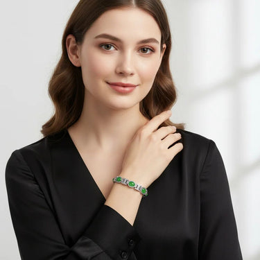 Woman wearing a bracelet with green gemstones on a plain background