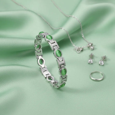 Jewelry set including a bracelet, necklace, and earrings on a green fabric background