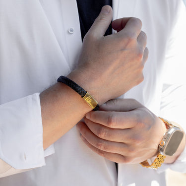 Close-up of a person wearing a gold watch and bracelet, adjusting their shirt.