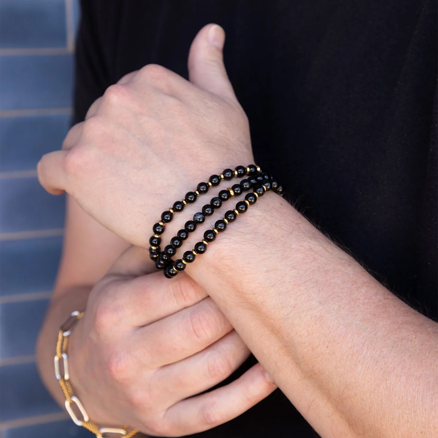 Close-up of hands wearing black beaded bracelets with a blurred background
