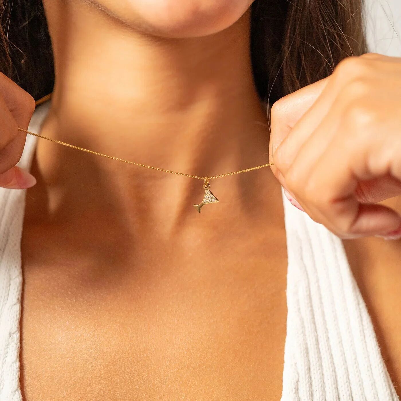 Gold necklace with a triangle pendant held by a person