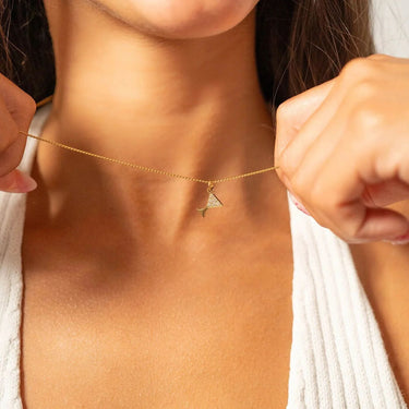 Gold necklace with a triangle pendant held by a person