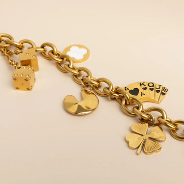 Gold lucky charms on bracelet with various charms on a beige background