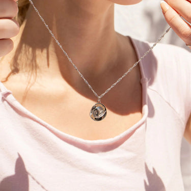 Silver necklace with a pendant worn by a person in a light pink top.