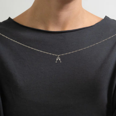 Person wearing a black shirt with a silver necklace featuring a small pendant.