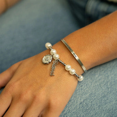 Bracelet with pearls and charms on a wrist against a denim background