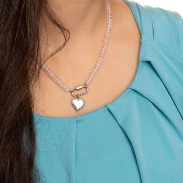 Necklace with a heart pendant worn by a person in a blue top