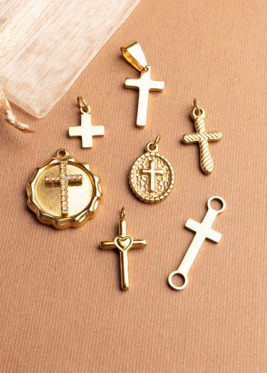 Gold cross religious pendants on a beige surface